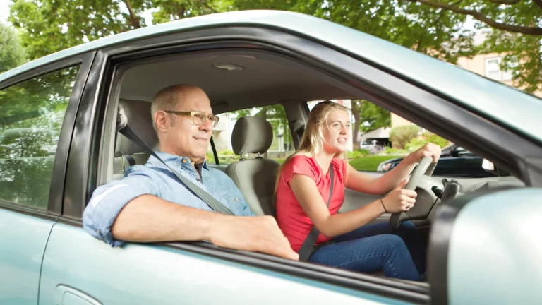 Parent or instructor guiding a teenage driver during a driving lesson