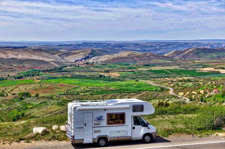 Image of a motor home on a scenic road, with a shield symbol representing Motor Home Insurance, highlighting protection against accidents, theft, and damages