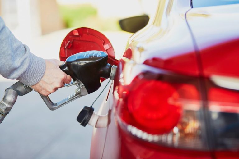 A person refueling their car at a gas station with the pump in focus